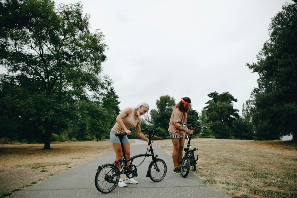 pexels-photo-9354889-9354889 Two adults with bicycles enjoy a leisurely day of cycling in a lush green park.