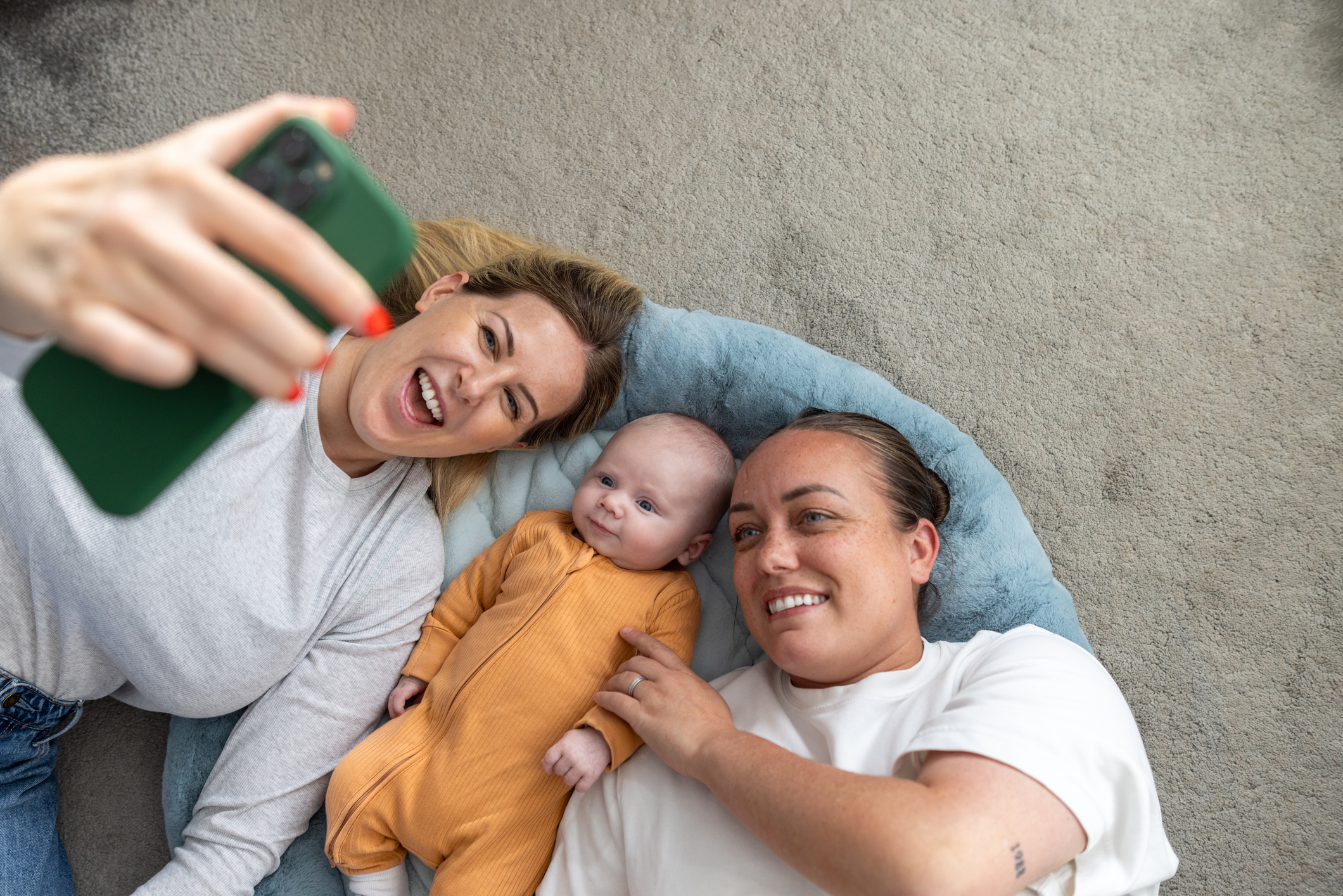 A joyful moment as two fathers feed their baby at home, showcasing love and family bonding.